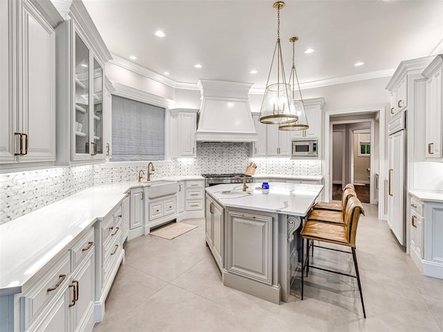 kitchen featuring sink, tasteful backsplash, built in appliances, a kitchen island, and custom range hood