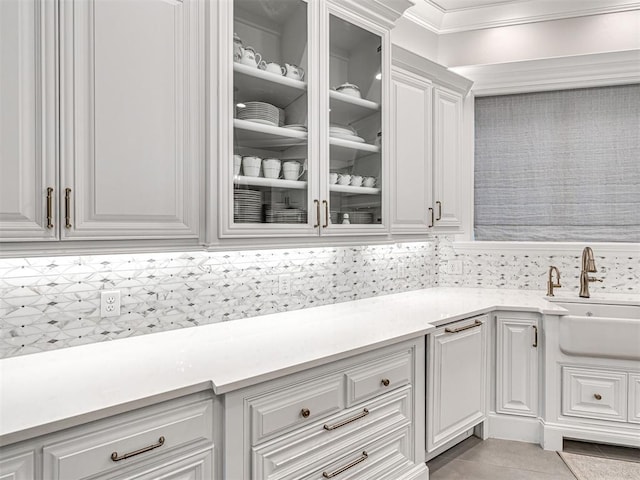 kitchen featuring decorative backsplash, crown molding, sink, light tile patterned floors, and white cabinets