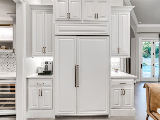 kitchen with wine cooler, crown molding, and white cabinets