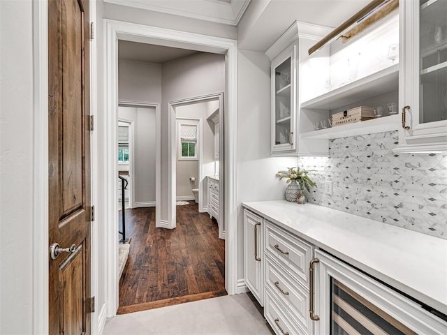 bar with white cabinets, decorative backsplash, dark hardwood / wood-style flooring, and crown molding