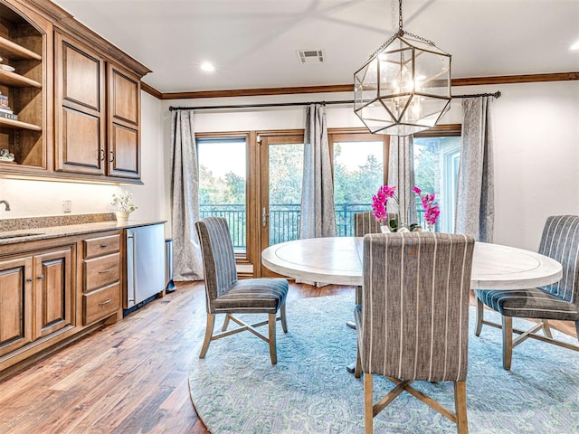 dining room featuring crown molding, light hardwood / wood-style flooring, an inviting chandelier, and sink