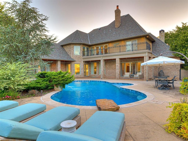 pool at dusk featuring a patio