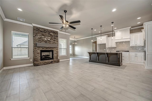 kitchen featuring a kitchen bar, a center island with sink, white cabinets, and decorative light fixtures