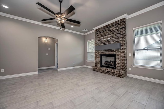 unfurnished living room featuring ceiling fan, light hardwood / wood-style floors, crown molding, and a fireplace