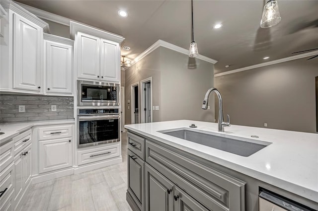 kitchen featuring white cabinets, sink, hanging light fixtures, tasteful backsplash, and stainless steel appliances