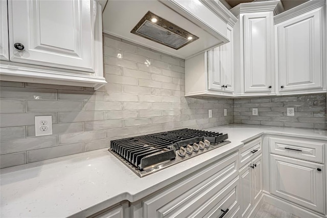 kitchen featuring white cabinets, decorative backsplash, premium range hood, and stainless steel gas stovetop