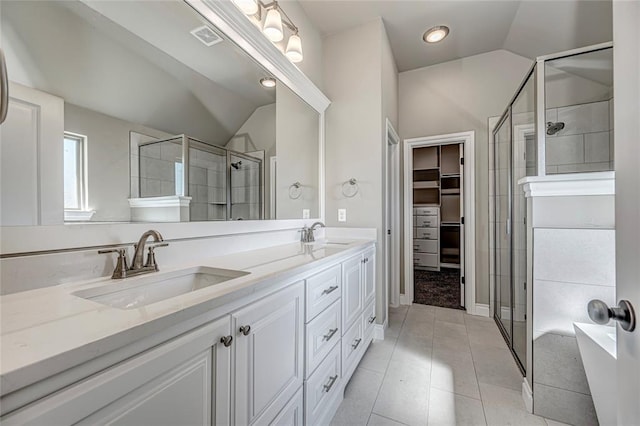 bathroom featuring tile patterned flooring, vanity, a shower with shower door, and vaulted ceiling