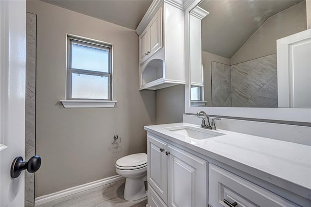 bathroom featuring toilet, vanity, hardwood / wood-style flooring, and vaulted ceiling