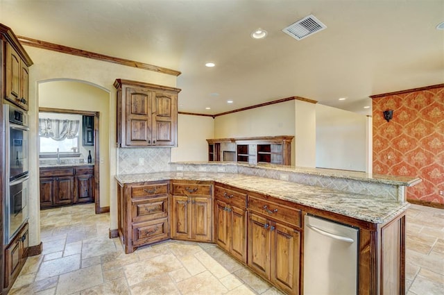 kitchen with decorative backsplash, appliances with stainless steel finishes, kitchen peninsula, light stone counters, and ornamental molding