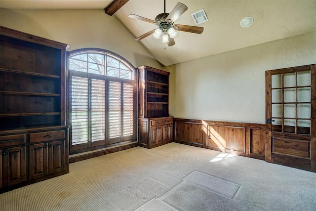 carpeted spare room featuring ceiling fan, lofted ceiling with beams, and wood walls