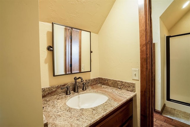 bathroom with vanity, wood-type flooring, and vaulted ceiling