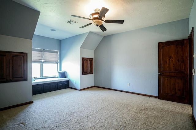 unfurnished bedroom with a textured ceiling, light colored carpet, ceiling fan, and lofted ceiling