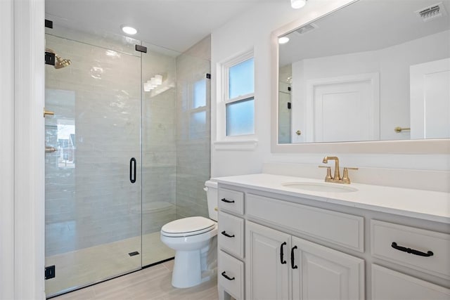 bathroom with a shower with door, vanity, and toilet