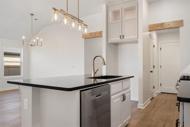 kitchen with stainless steel dishwasher, sink, white cabinets, hanging light fixtures, and an island with sink