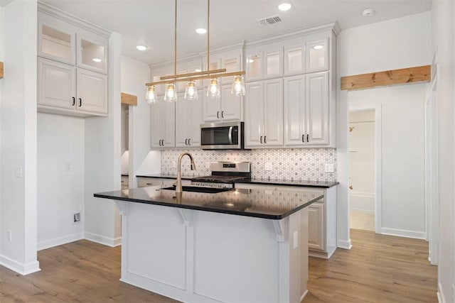 kitchen with a kitchen breakfast bar, a center island with sink, white cabinets, and appliances with stainless steel finishes