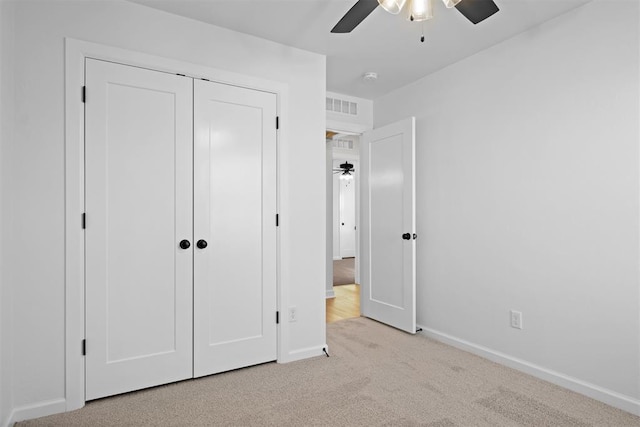 unfurnished bedroom with ceiling fan, light colored carpet, and a closet