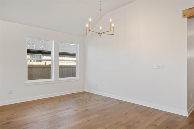 unfurnished dining area with an inviting chandelier, vaulted ceiling, and light wood-type flooring