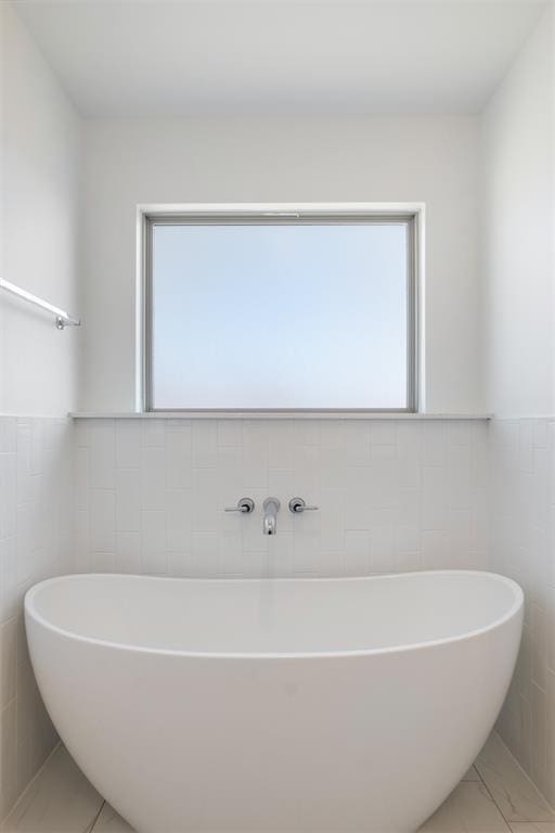 bathroom with a bath and tile walls