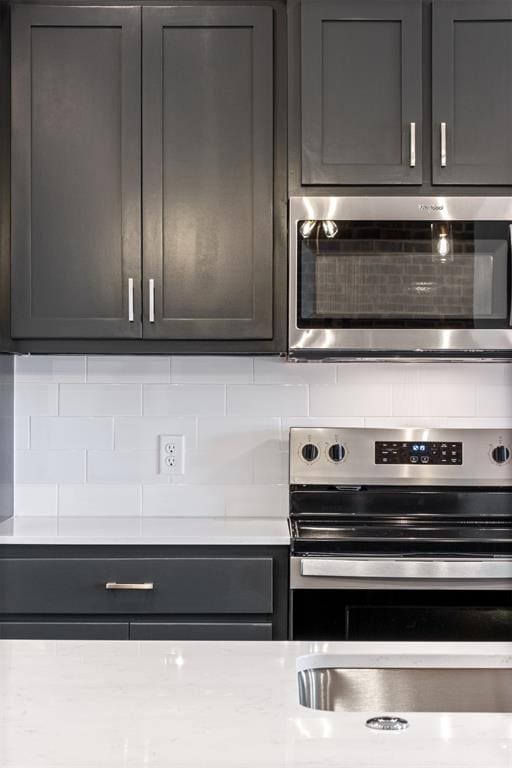 kitchen with stainless steel electric stove and backsplash