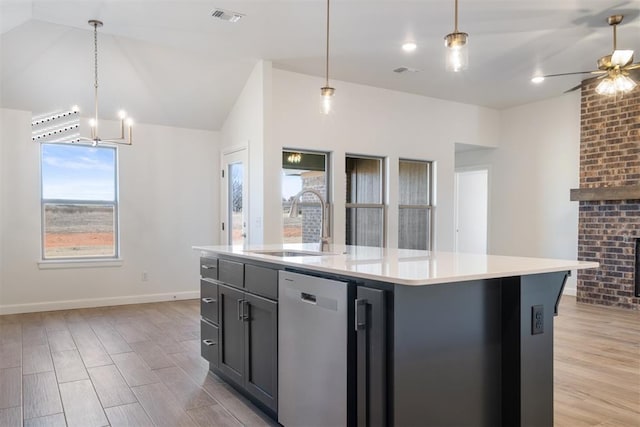 kitchen featuring a center island with sink, ceiling fan with notable chandelier, sink, hanging light fixtures, and stainless steel dishwasher