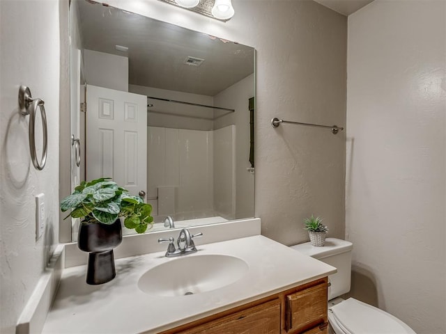 bathroom featuring a shower, vanity, and toilet