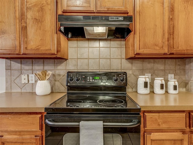 kitchen featuring tile patterned flooring, black range with electric cooktop, tasteful backsplash, and exhaust hood