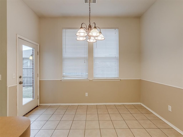 tiled spare room featuring a notable chandelier