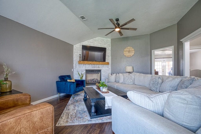 living room with ceiling fan, dark hardwood / wood-style flooring, lofted ceiling, and a fireplace