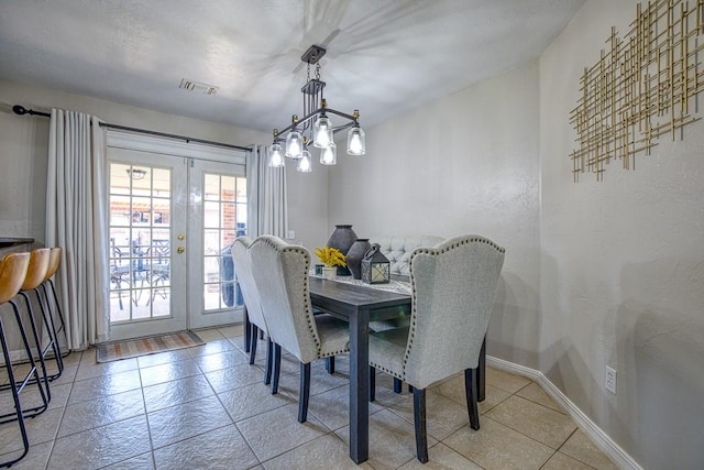 tiled dining area featuring french doors and an inviting chandelier