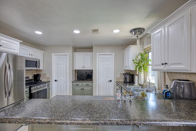 kitchen featuring white cabinets, sink, decorative backsplash, appliances with stainless steel finishes, and kitchen peninsula