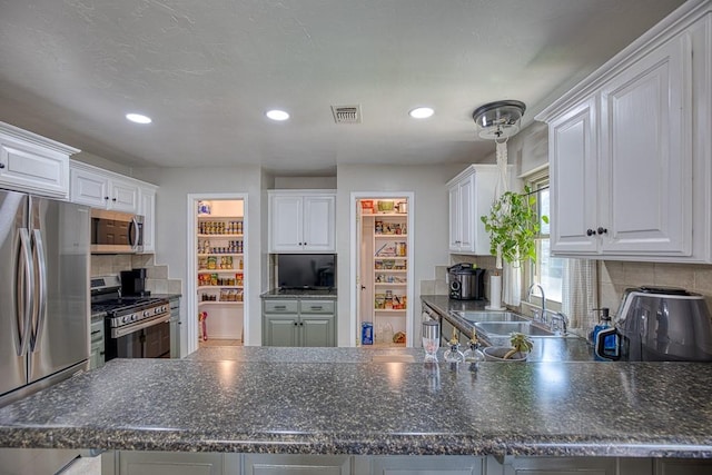 kitchen with white cabinetry, sink, backsplash, kitchen peninsula, and appliances with stainless steel finishes