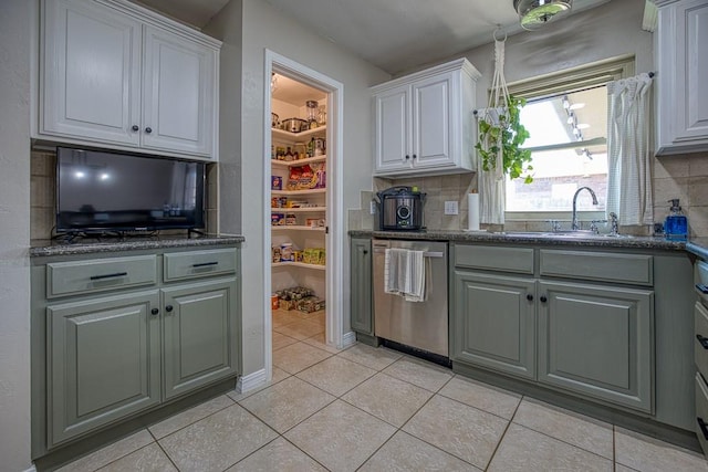 kitchen featuring decorative backsplash, stainless steel dishwasher, sink, white cabinetry, and light tile patterned flooring