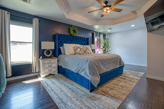 bedroom featuring ceiling fan, crown molding, dark wood-type flooring, and a tray ceiling