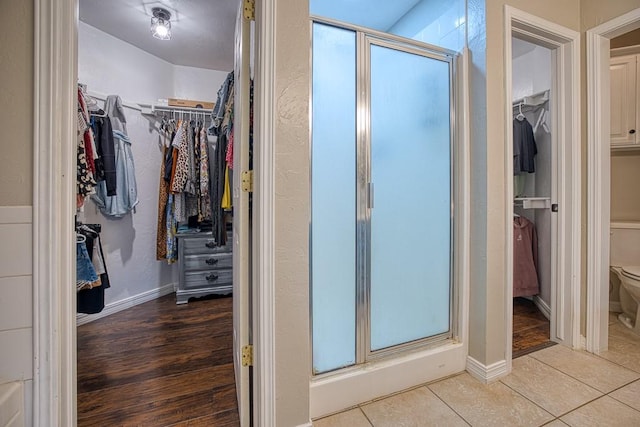 bathroom featuring tile patterned floors, toilet, and a shower with shower door