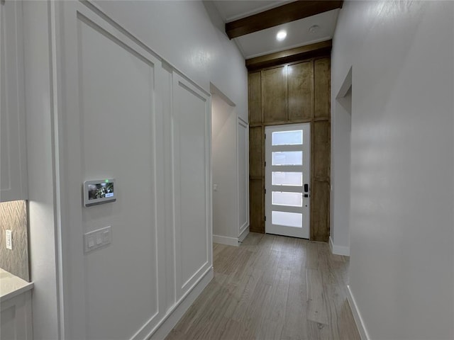 doorway featuring beam ceiling and light hardwood / wood-style floors