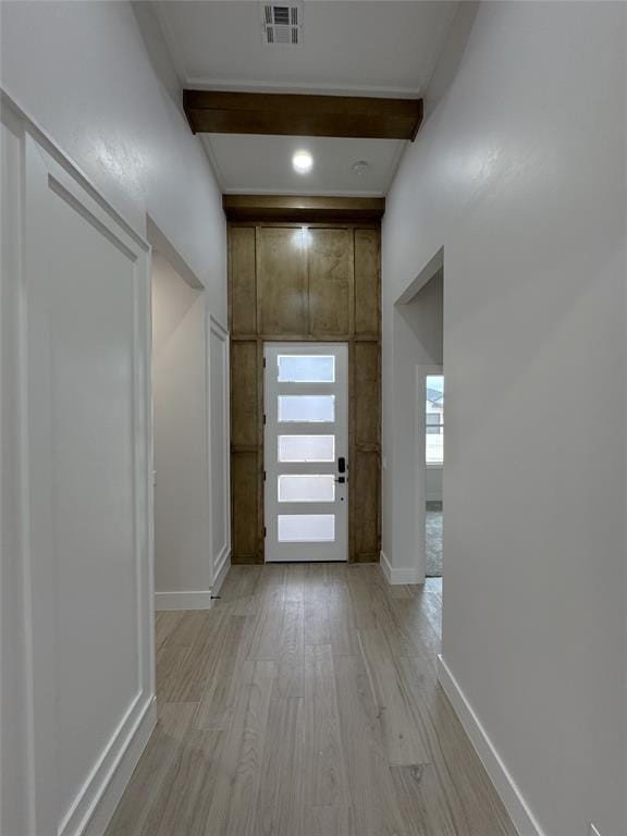 hall with light hardwood / wood-style flooring and beamed ceiling