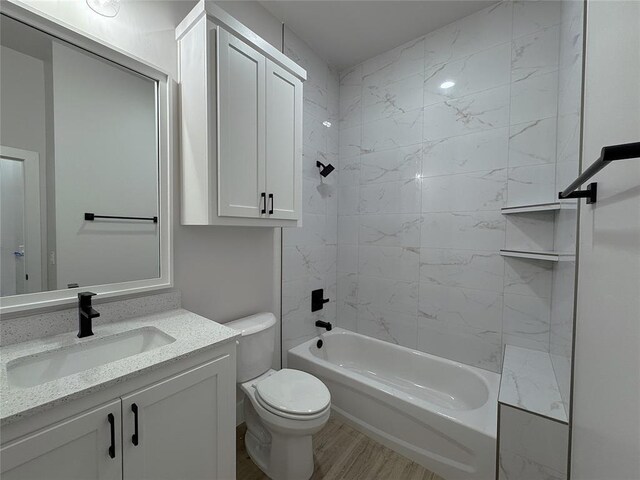 full bathroom featuring vanity, hardwood / wood-style floors, tiled shower / bath combo, and toilet