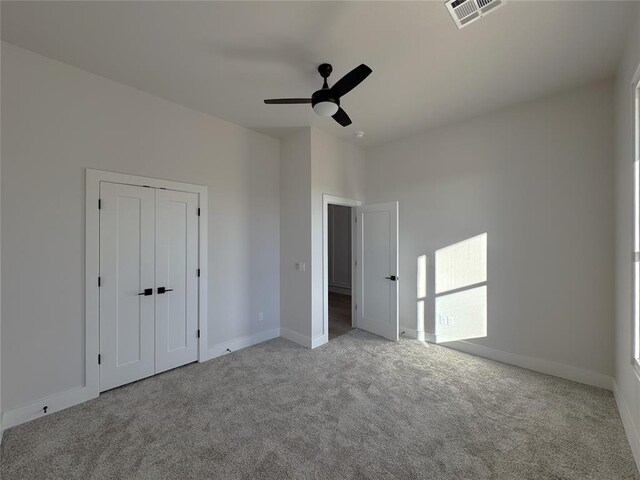 unfurnished bedroom featuring a closet, light colored carpet, and ceiling fan