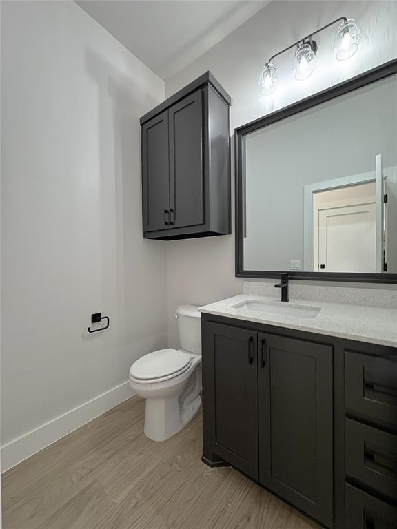 bathroom with hardwood / wood-style floors, vanity, and toilet