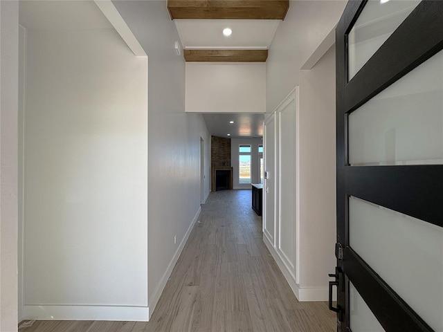 hallway featuring beamed ceiling and light hardwood / wood-style floors