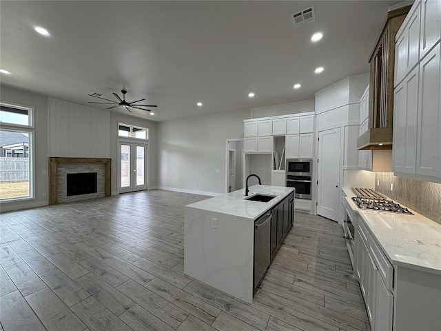 kitchen with a kitchen island with sink, sink, white cabinets, and stainless steel appliances