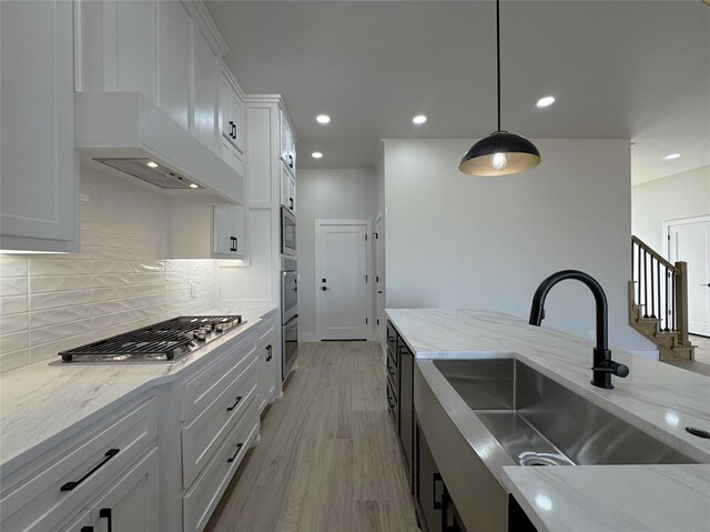 kitchen with white cabinets, light stone countertops, hanging light fixtures, and sink