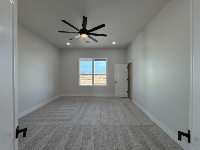 empty room featuring ceiling fan and light carpet