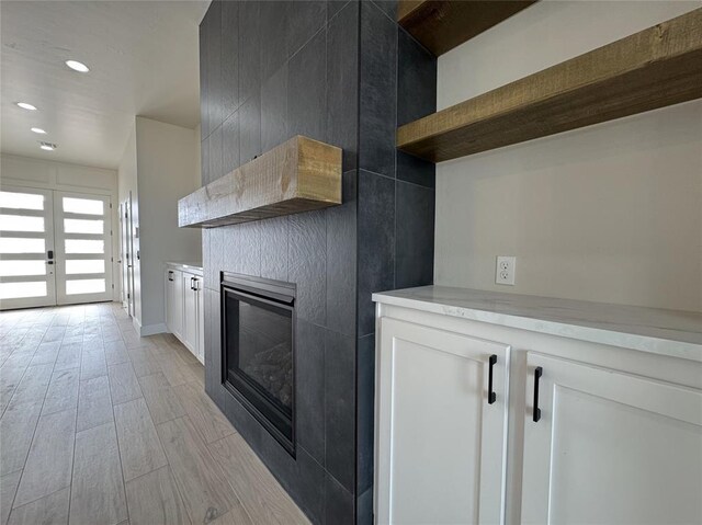 kitchen with light wood-type flooring, white cabinetry, and french doors