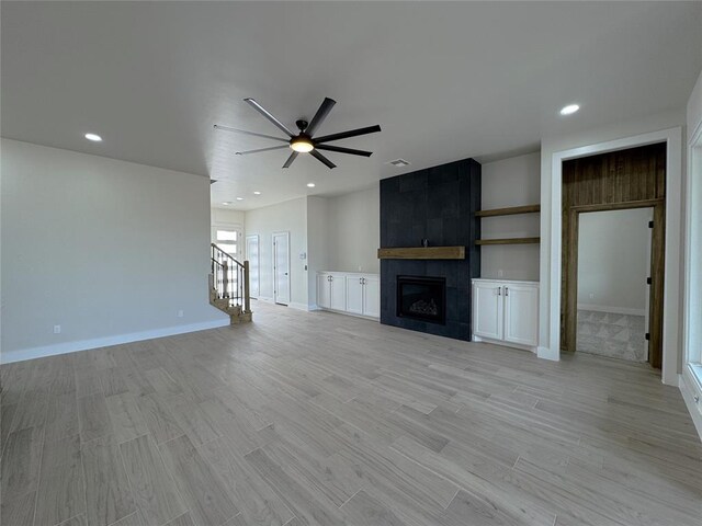 unfurnished living room with a tile fireplace, ceiling fan, and light hardwood / wood-style flooring