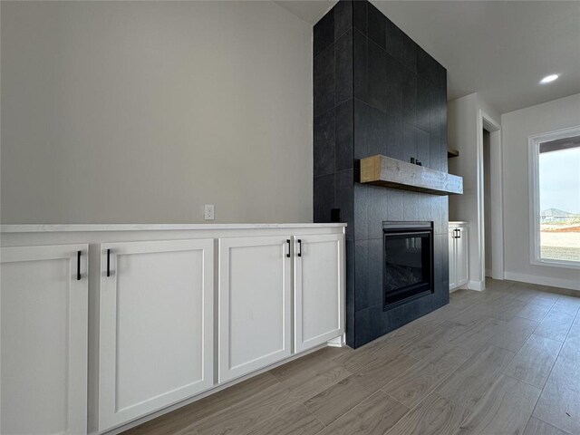 kitchen with a fireplace, light wood-type flooring, and white cabinetry