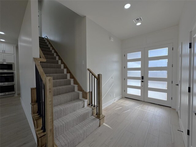 foyer entrance featuring french doors and light hardwood / wood-style flooring