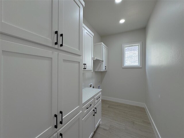 laundry area featuring washer hookup, hookup for an electric dryer, cabinets, and light wood-type flooring