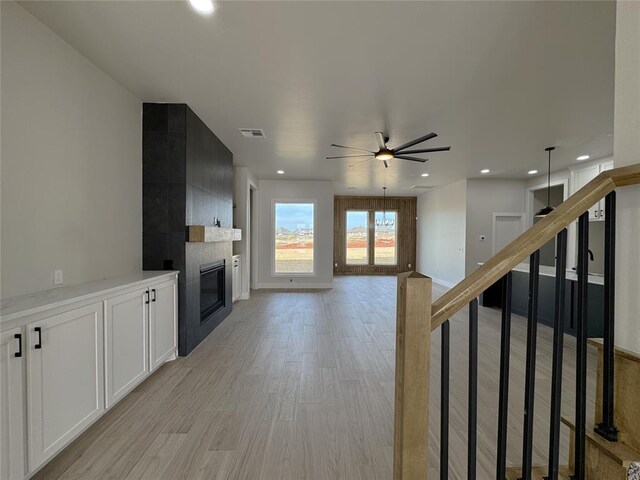 unfurnished living room featuring ceiling fan, a fireplace, and light hardwood / wood-style flooring