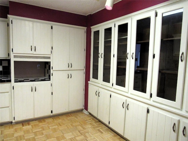 kitchen with white cabinets, light parquet flooring, and a textured ceiling